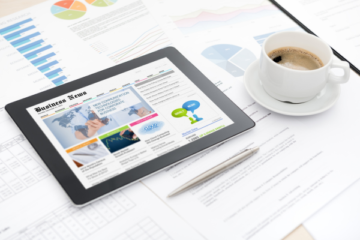 Image of a tablet on a table, showing a business article.