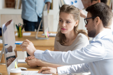 A photo showing a couple discussing a marketing project at a computer.