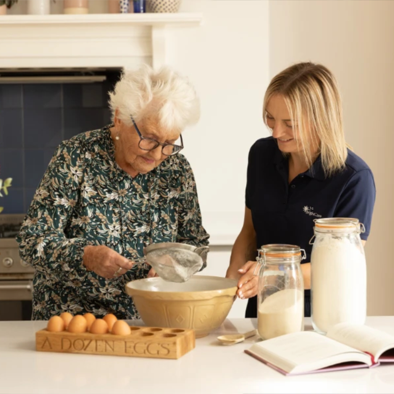 A photo from Bright Care - showing a carer and an elderly client baking a cake.